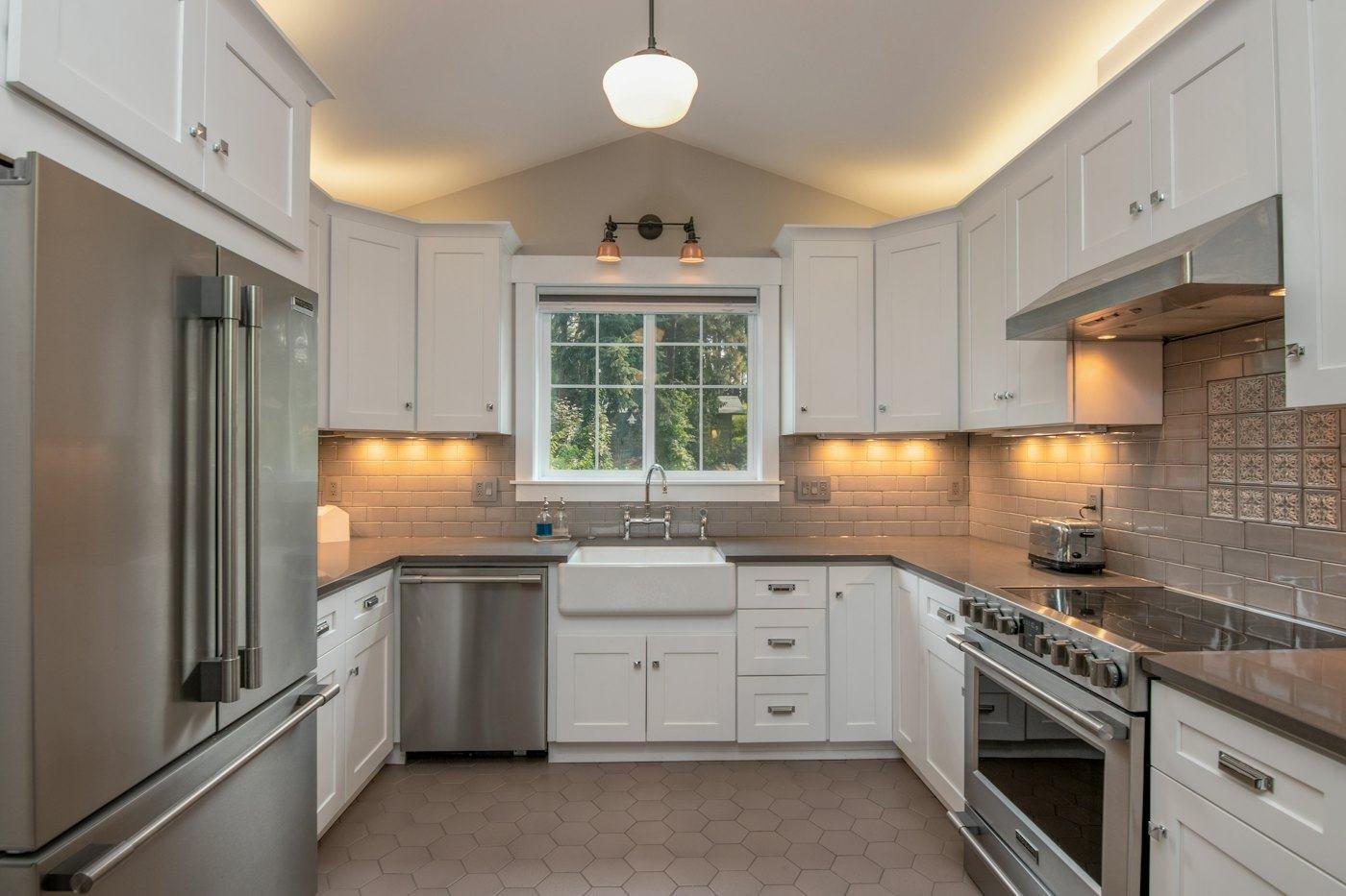 White shaker kitchen with stone countertops and warm lighting